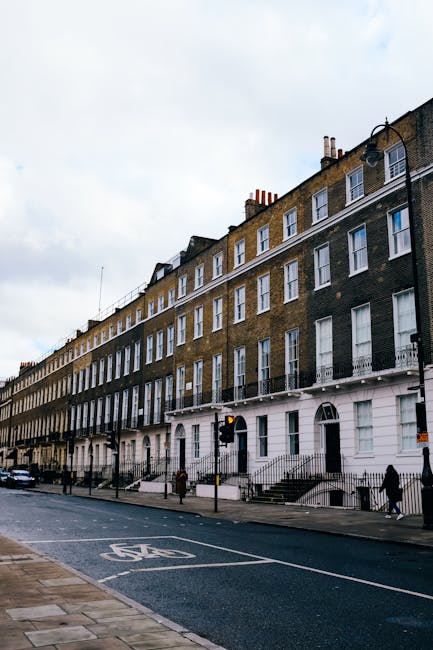 Photograph of the exterior of The Marylebone pub on Baker Street, London, showing an aged grey sign with black text and a black border, mounted on the corner of a red-brick building. The sign displays